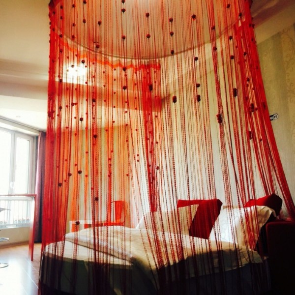 шторы нити красного цвета с узелками в интерьере спальни 
