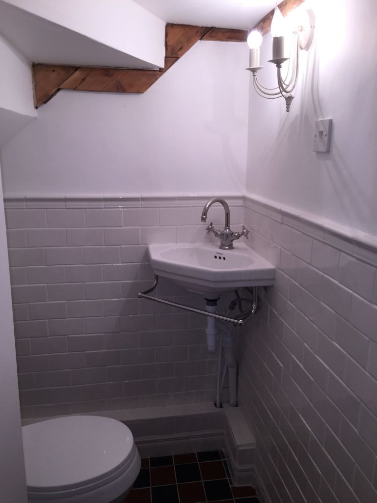 Угловая раковина в туалете под лестницей