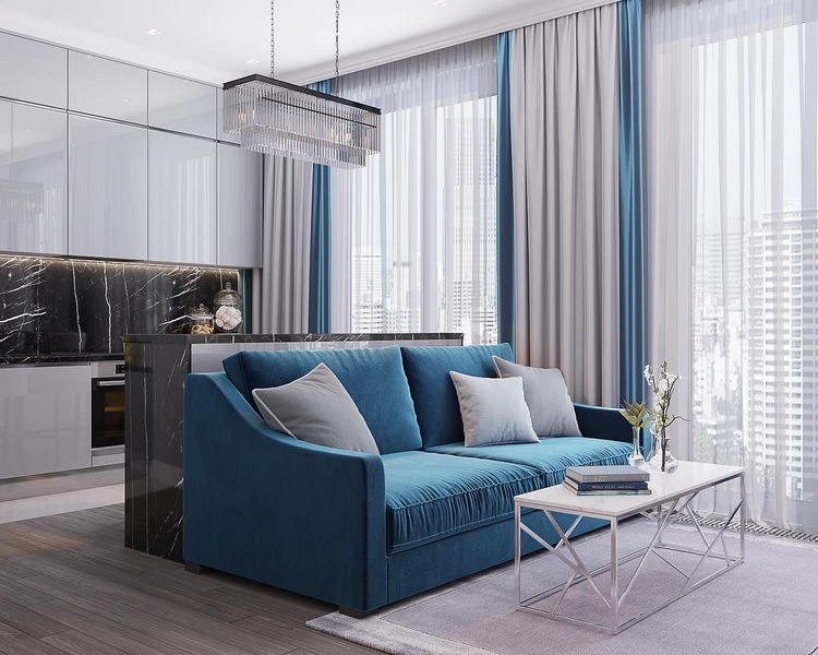 Синий диван в белом интерьере гостиной совмещенной с кухней