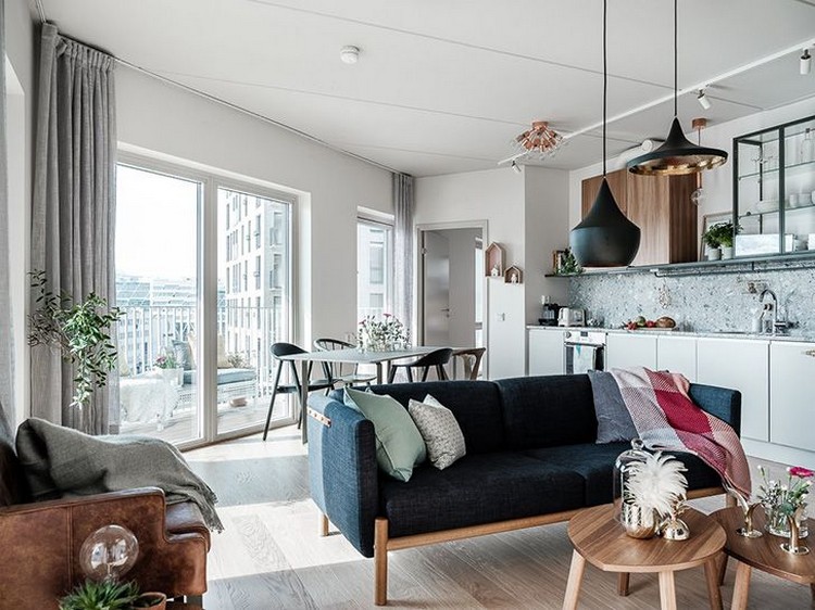 Синий диван в скандинавском интерьере гостиной совмещенной с кухней